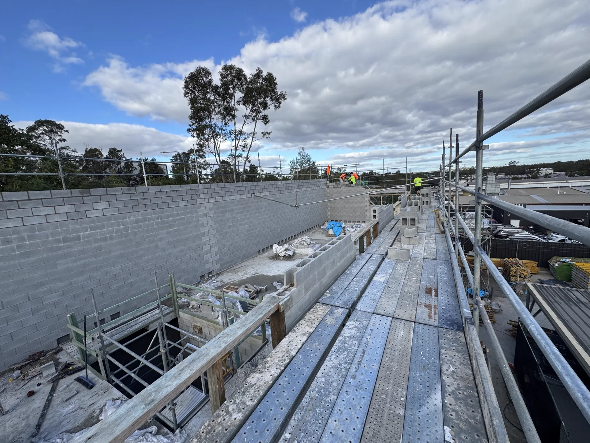 Long runs of structural concrete blockwork on a large commercial site with full perimeter scaffold.