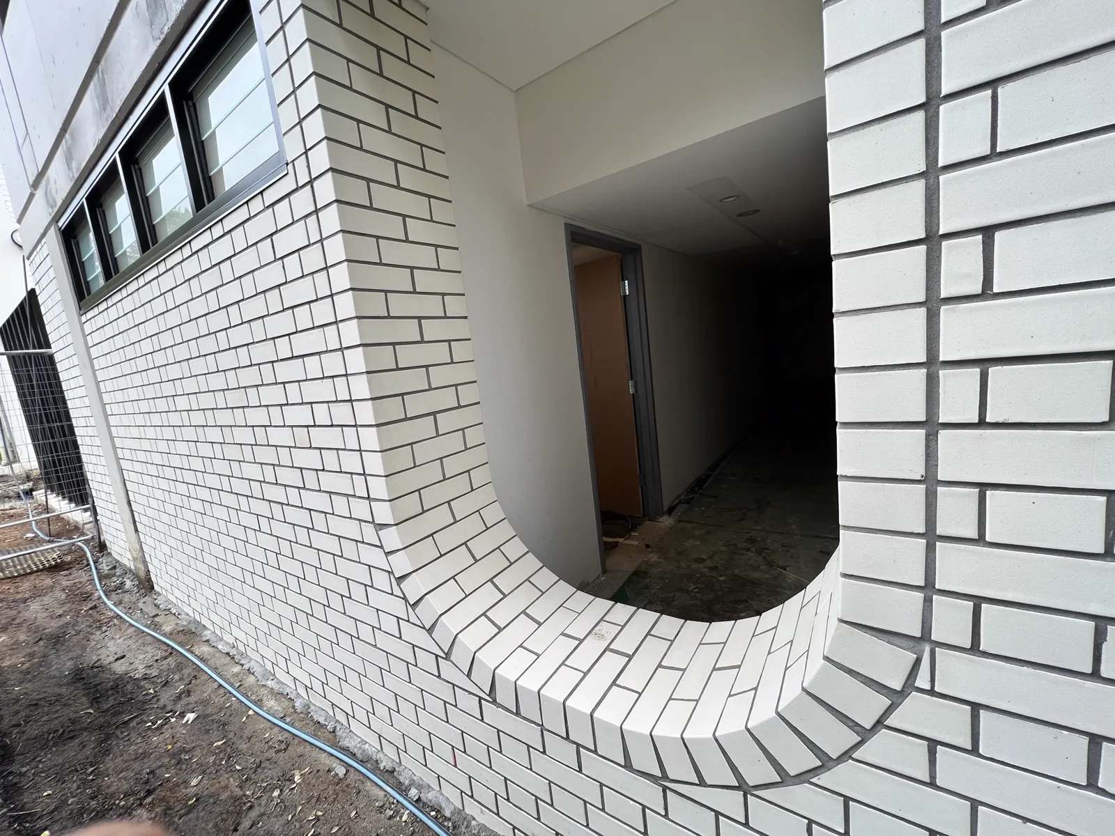 Wide curved white brick reveal to a covered walkway entry, showing the radial sill and rolled returns.