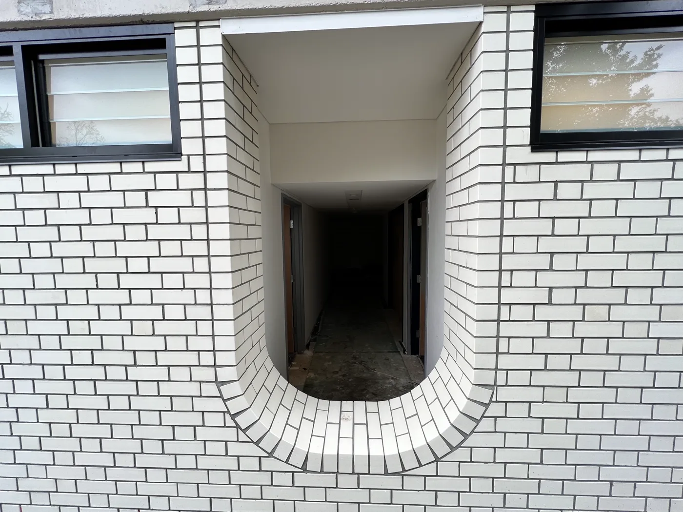 Close view of a curved white brick doorway reveal with a radial brick threshold.