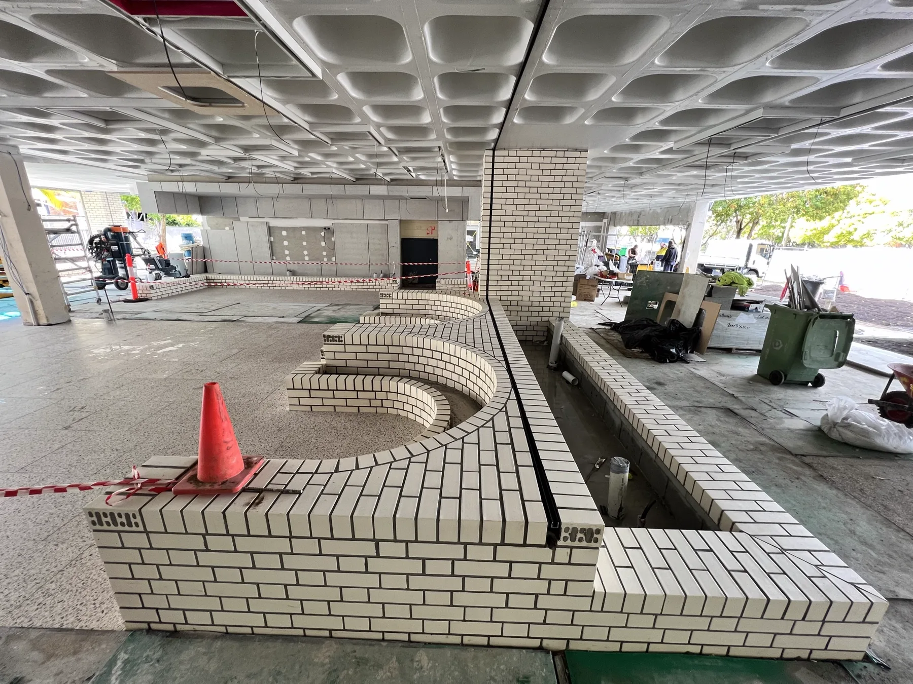 Curved white face-brick amphitheatre seating wall under a waffle-slab soffit at St Margaret's Anglican Girls School, Ascot.