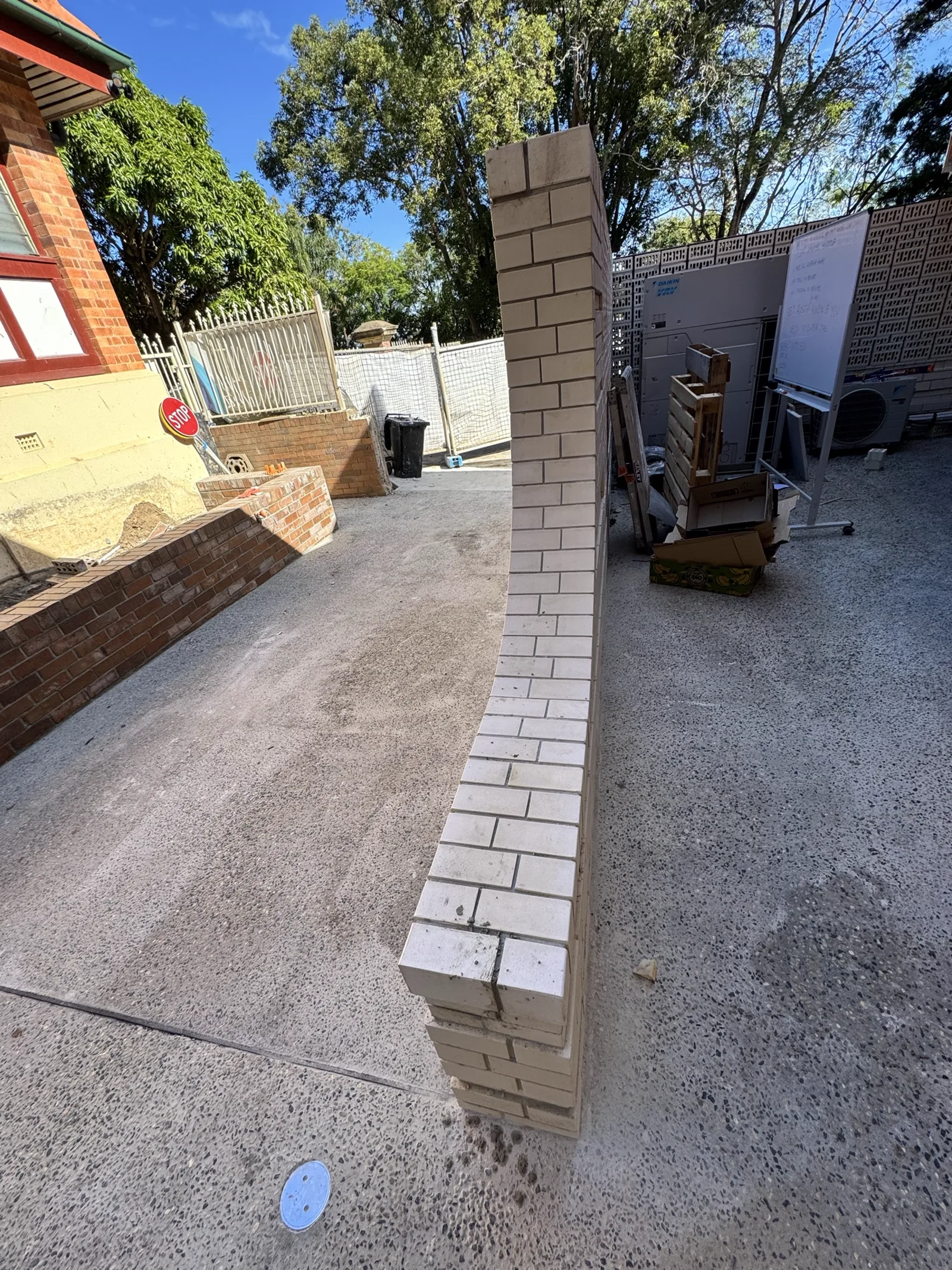Set-out of a curved feature wall in light sand face brick, laid to a swept radius off a site-marked template.